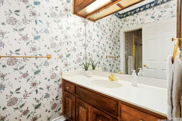 bathroom featuring wallpapered walls, a shower, and vanity