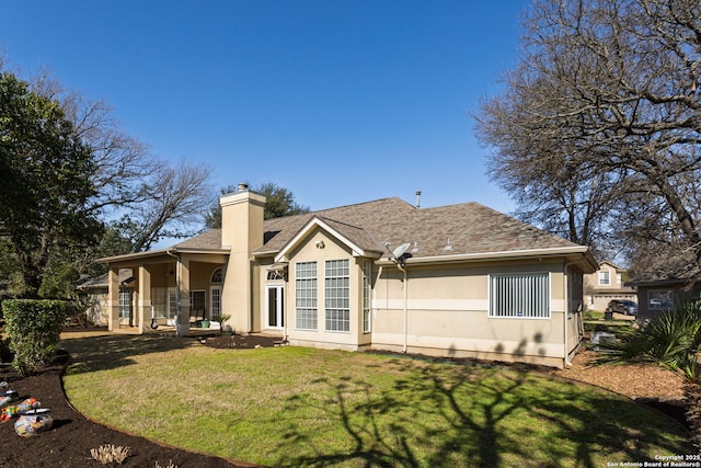 back of house featuring a shingled roof, a lawn, a chimney, and stucco siding