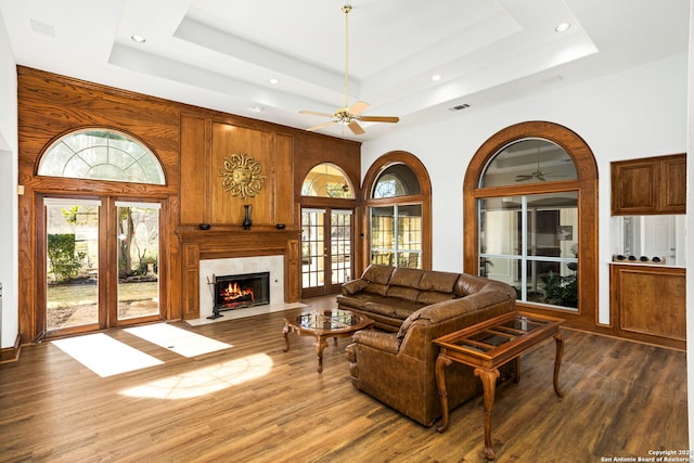 living room with dark wood-style floors, french doors, a tray ceiling, and a healthy amount of sunlight