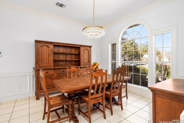 dining area with light tile patterned floors, a notable chandelier, visible vents, and crown molding