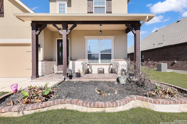 doorway to property with central air condition unit, a garage, and stucco siding