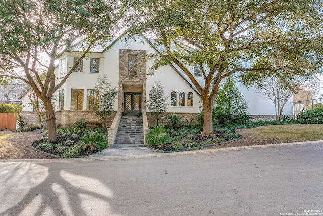 view of front of house featuring brick siding, fence, and stucco siding