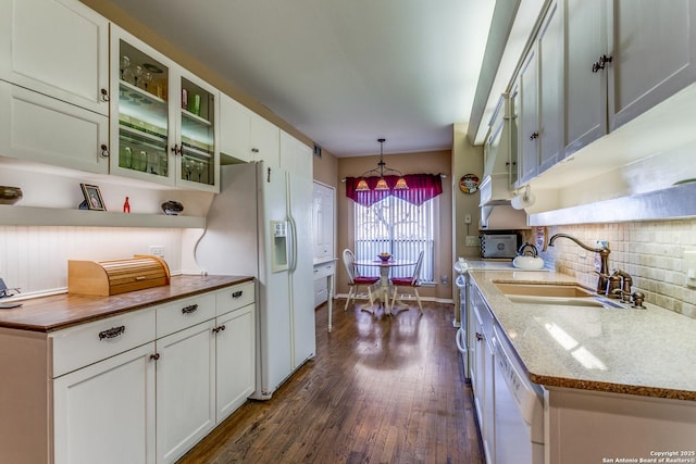 kitchen featuring white appliances, dark wood-style flooring, a sink, hanging light fixtures, and backsplash