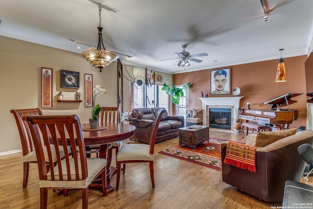 interior space featuring a fireplace with flush hearth, wood finished floors, a ceiling fan, and crown molding