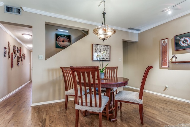 dining space featuring ornamental molding, visible vents, baseboards, and wood finished floors