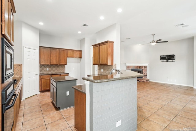 kitchen with visible vents, stainless steel microwave, black oven, a sink, and light tile patterned flooring