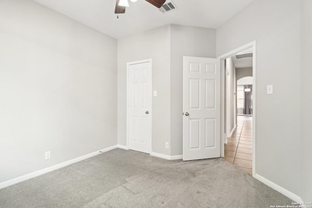 unfurnished bedroom with carpet floors, baseboards, visible vents, and arched walkways