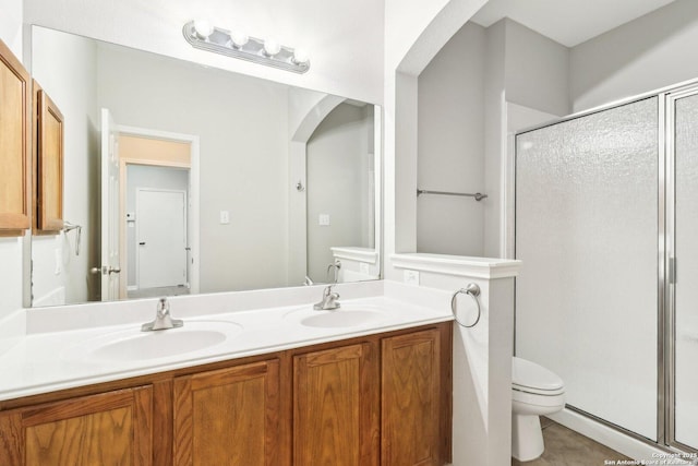 bathroom featuring a sink, a shower stall, toilet, and double vanity