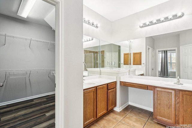 bathroom featuring a shower stall, two vanities, a sink, and tile patterned floors