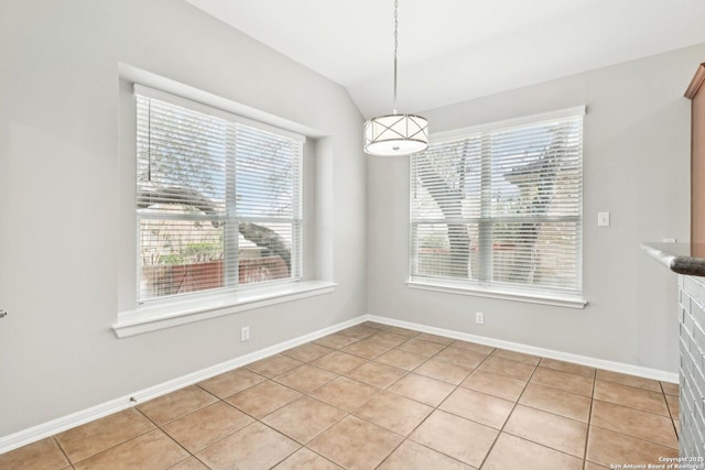 unfurnished dining area featuring vaulted ceiling, baseboards, and light tile patterned floors