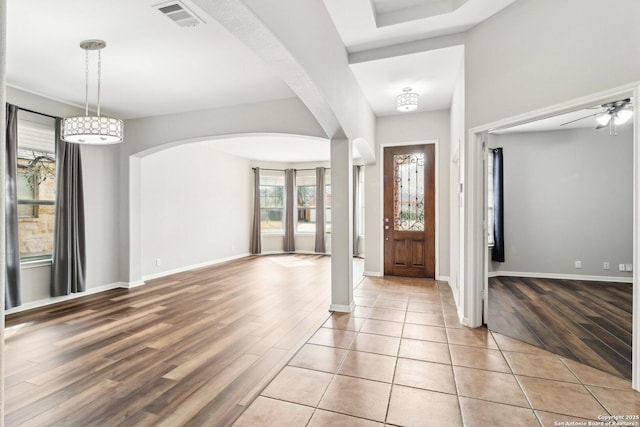 entryway with arched walkways, ceiling fan, visible vents, baseboards, and light wood-style floors