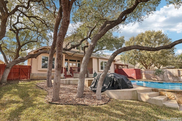 rear view of house with a yard, a fenced backyard, a fenced in pool, and a patio