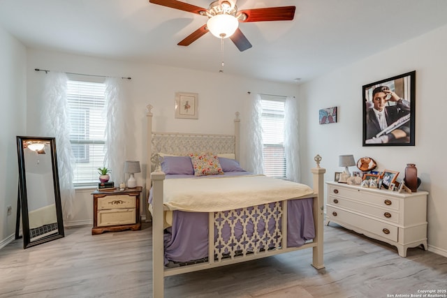 bedroom with a ceiling fan, light wood-type flooring, multiple windows, and baseboards