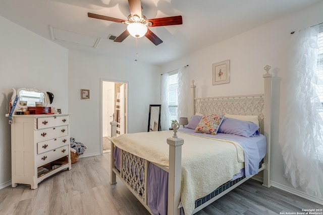 bedroom featuring light wood finished floors, visible vents, attic access, a ceiling fan, and baseboards