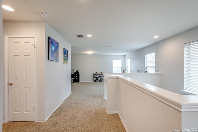 hallway featuring recessed lighting, light carpet, visible vents, baseboards, and an upstairs landing