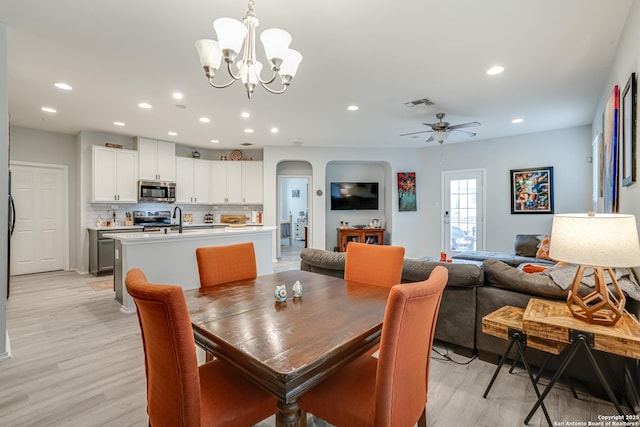 dining space with light wood-style floors, arched walkways, visible vents, and recessed lighting