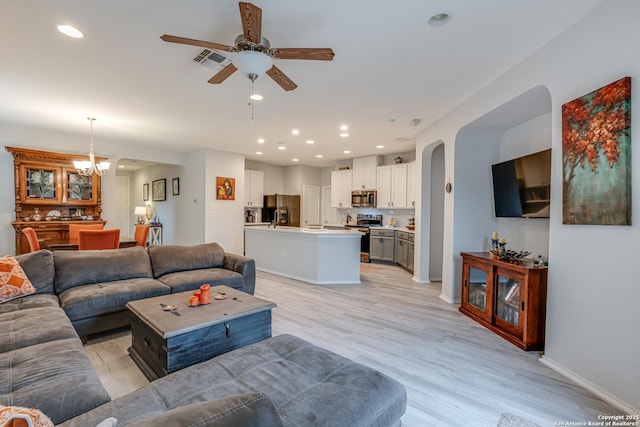 living room featuring ceiling fan with notable chandelier, recessed lighting, visible vents, and light wood-style floors