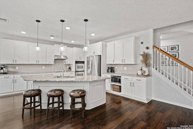 kitchen with appliances with stainless steel finishes, dark wood-type flooring, a sink, and white cabinetry