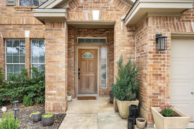 entrance to property with a garage and brick siding