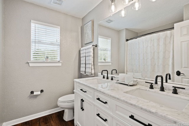 bathroom featuring toilet, a sink, visible vents, and baseboards