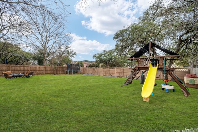 view of yard with a trampoline, a playground, and a fenced backyard