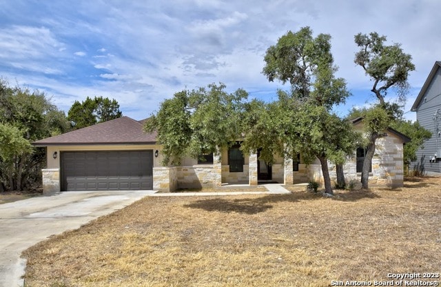 view of front of house featuring stone siding, an attached garage, and driveway