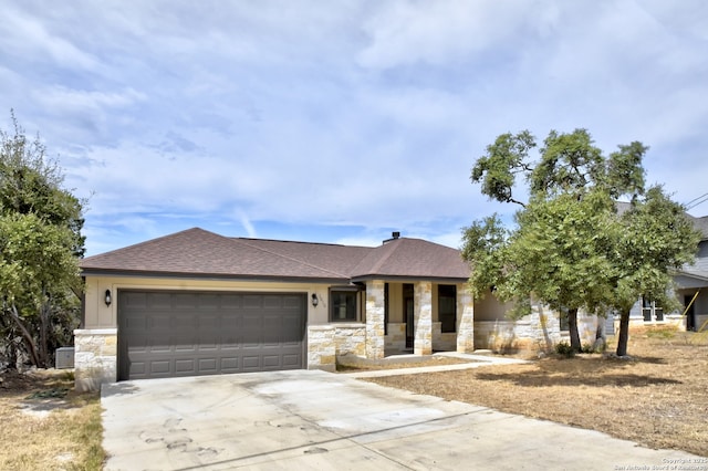 view of front of home with a garage, stone siding, a shingled roof, and driveway