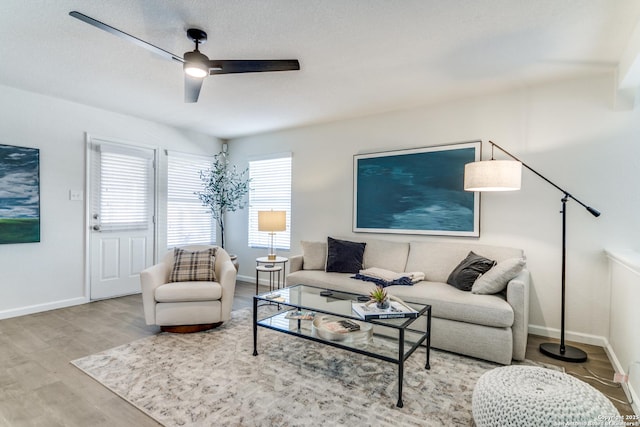 living room featuring ceiling fan, wood finished floors, and baseboards