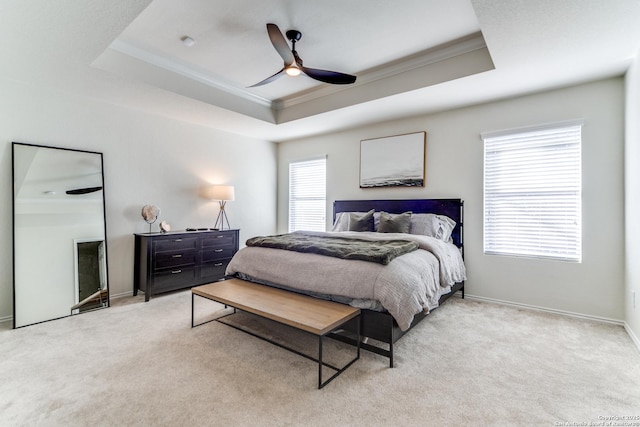 carpeted bedroom with baseboards, a tray ceiling, a ceiling fan, and ornamental molding