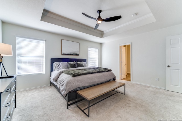 bedroom with light carpet, a tray ceiling, and baseboards