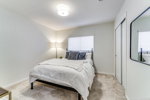 carpeted bedroom with a closet and baseboards