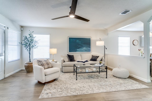 living room featuring a wealth of natural light, visible vents, and wood finished floors