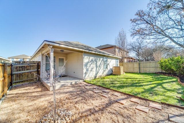 rear view of property with a fenced backyard, a lawn, and a patio