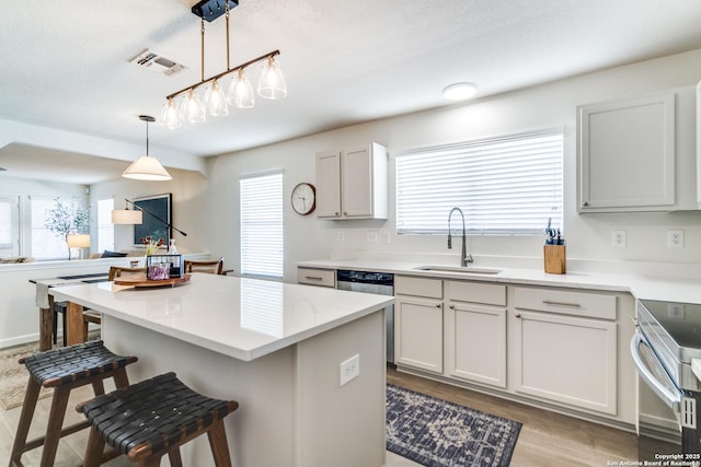 kitchen featuring a healthy amount of sunlight, visible vents, a sink, and a kitchen bar