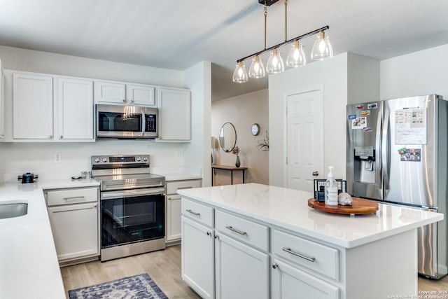 kitchen with stainless steel appliances, a kitchen island, light wood-style flooring, and white cabinetry