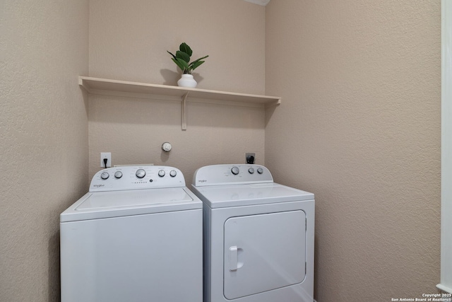 laundry room with washer and clothes dryer, laundry area, and a textured wall