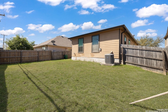 back of house with central air condition unit, a lawn, and a fenced backyard