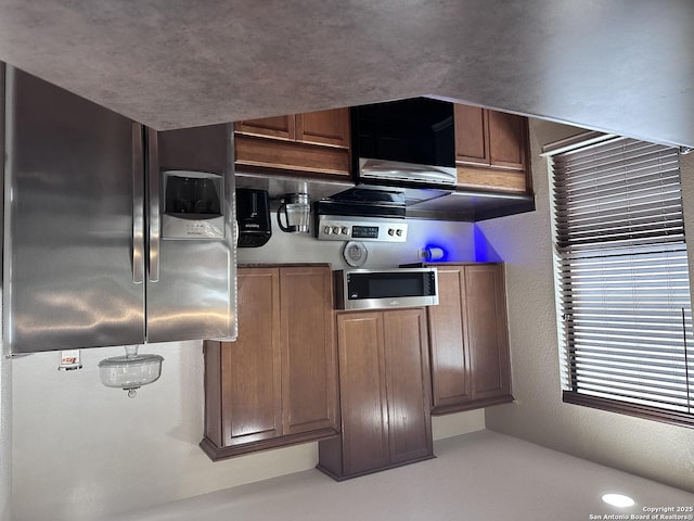 kitchen with brown cabinets, stainless steel appliances, and a textured wall