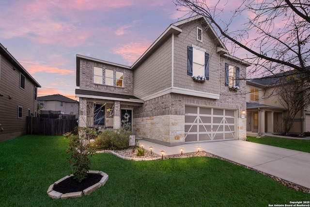 traditional-style home with concrete driveway, stone siding, an attached garage, fence, and a front lawn