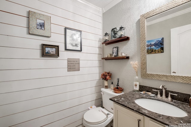 bathroom with toilet, vanity, crown molding, and a textured wall