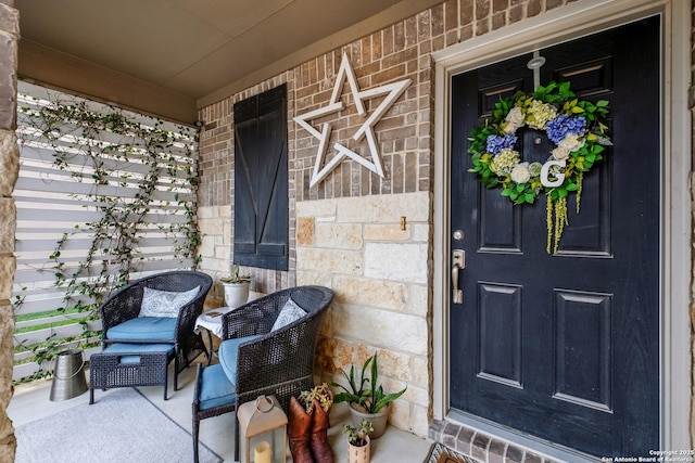view of exterior entry featuring a porch, stone siding, and brick siding