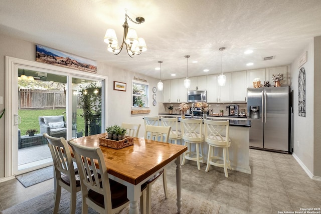 dining space featuring visible vents, a notable chandelier, a textured ceiling, and baseboards