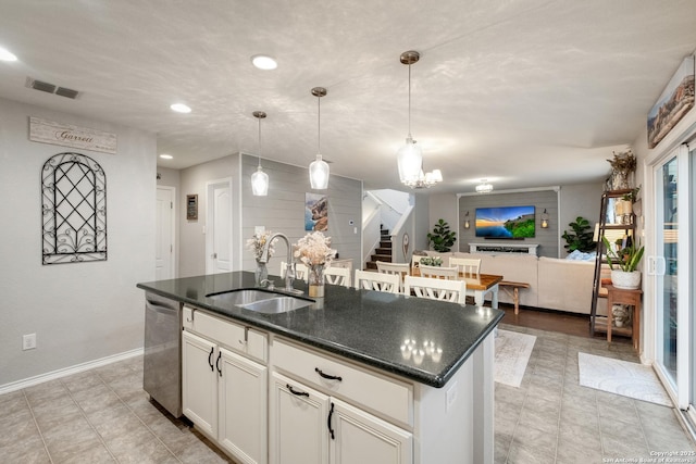 kitchen with visible vents, stainless steel dishwasher, open floor plan, a kitchen island with sink, and a sink