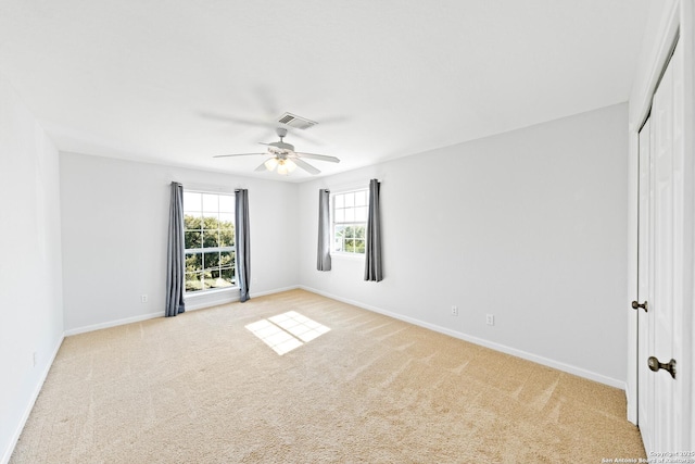 empty room with baseboards, a ceiling fan, visible vents, and light colored carpet