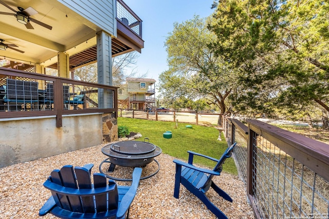 view of yard with a fire pit, ceiling fan, and fence