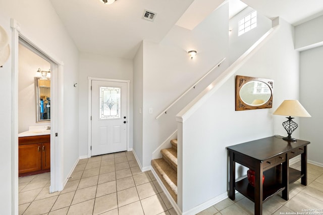 foyer with visible vents, stairway, baseboards, and light tile patterned flooring