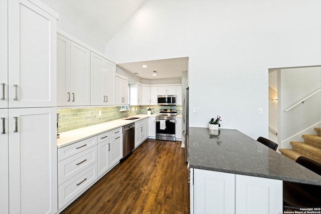 kitchen with vaulted ceiling, stainless steel appliances, a sink, and a kitchen breakfast bar