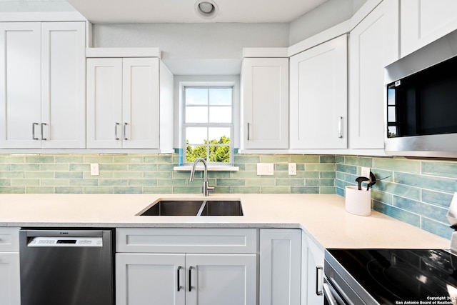 kitchen with stainless steel appliances, white cabinetry, a sink, and decorative backsplash