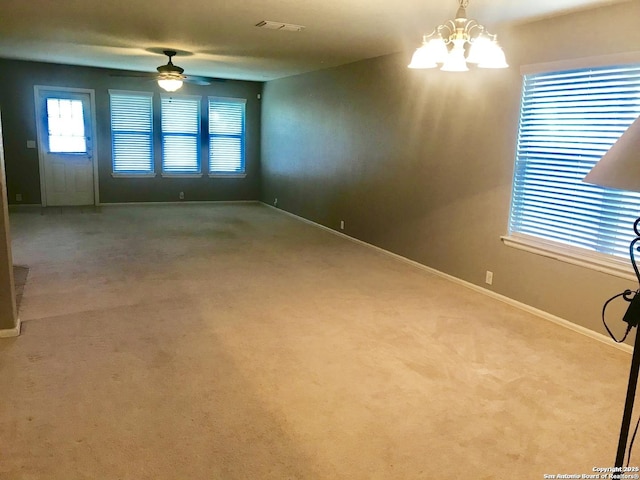 empty room featuring carpet, visible vents, baseboards, and ceiling fan with notable chandelier