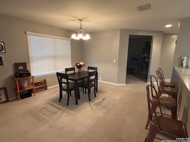 carpeted dining space featuring baseboards, visible vents, and an inviting chandelier